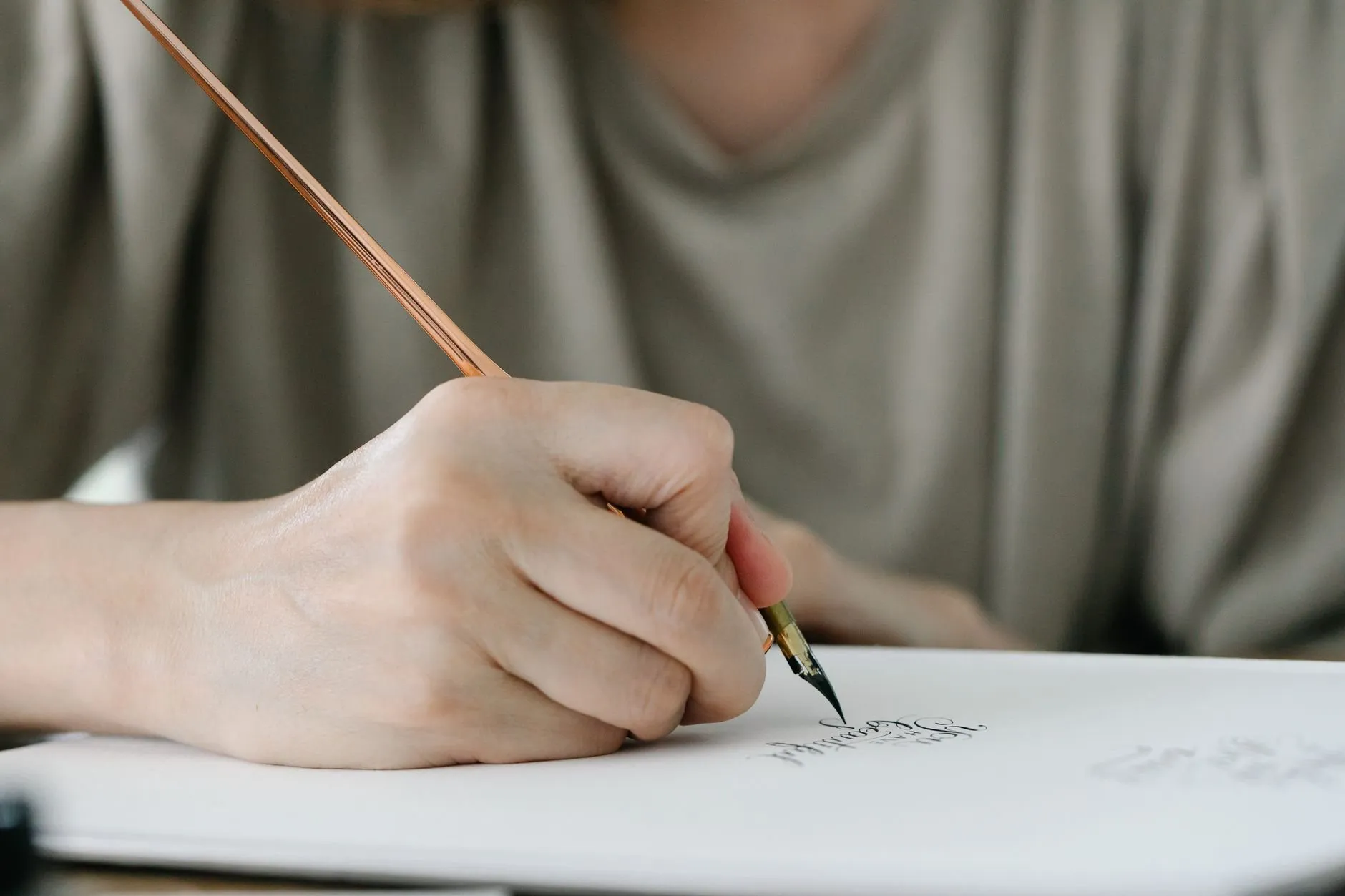 The writer's hand with a dip pen over a notebook